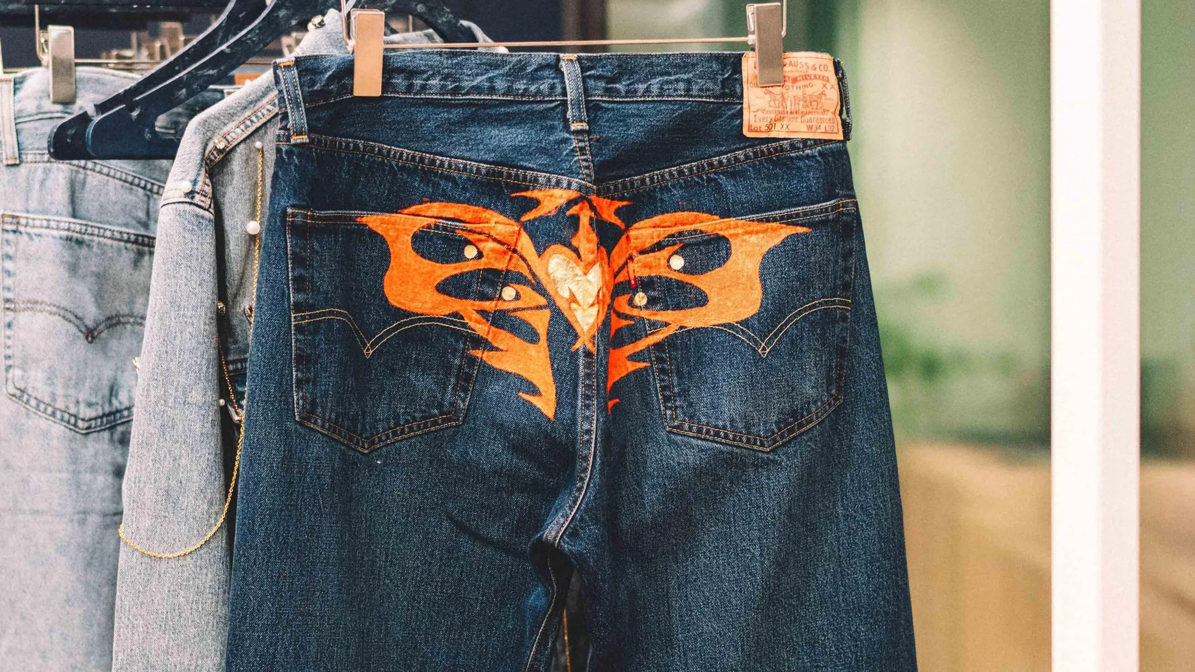 Levi&rsquo;s jeans with a hand-painted orange design across the back pockets