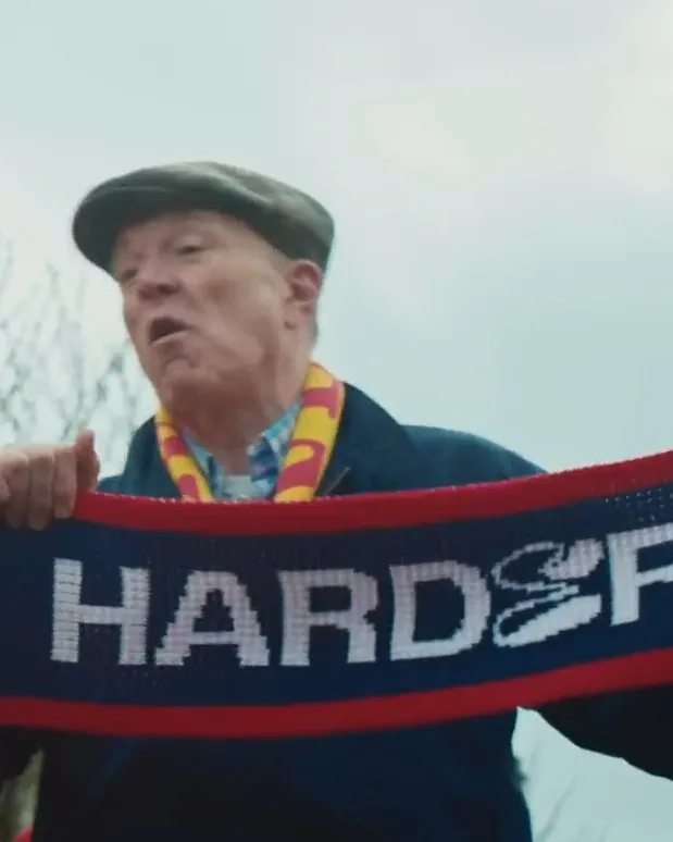 A fan holding up a scarf in the Ted Lasso campaign